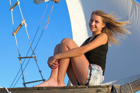 Beautiful teen girl sitting at stern of the shipの写真素材