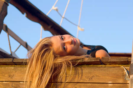 Pretty girl lying on the deck of an old wooden shipの写真素材