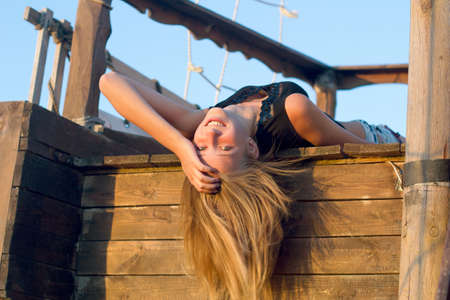 Joyful girl lying on the deck of an old wooden shipの写真素材