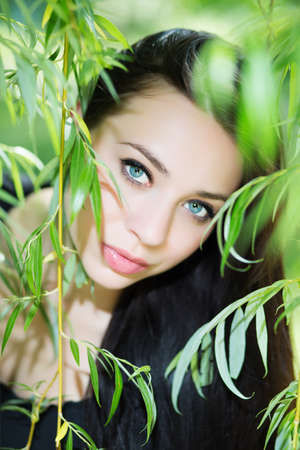 Thoughtful young brunette posing in the green branchesの写真素材