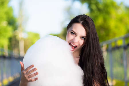 Young brunette eating a cotton candy outdoorsの写真素材