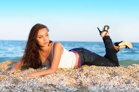 Pretty thoughtful brunette lying on the beachの写真素材