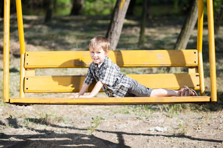 Funny little boy posing on a swing in the parkの写真素材