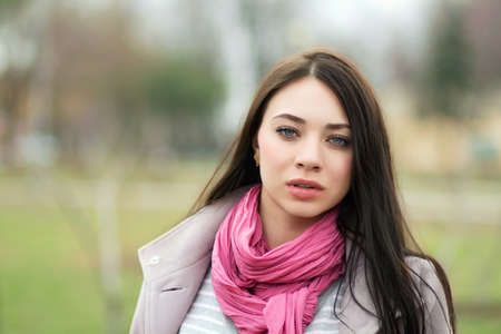 Portrait of young brunette with pink scarf posing outsideの写真素材