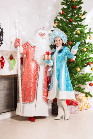 Santa claus and snow maiden posing near christmas treeの写真素材