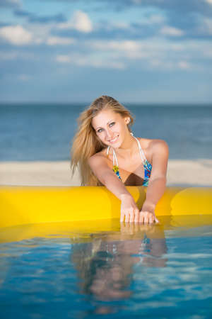 Young sexy blonde posing near yellow pool