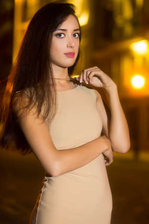 Portrait of pretty brunette in beige dress posing outdoorsの写真素材