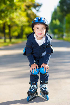 Smiling little boy rollerblading down the sidewalk
