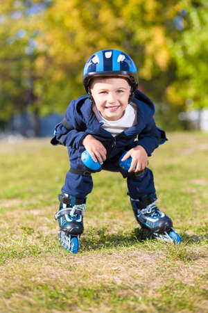 Smiling little boy riding on roller skates in the parkの写真素材