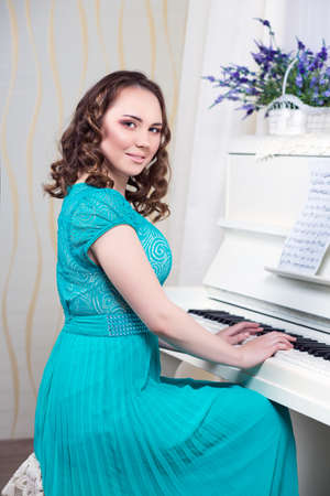 Smiling woman in turquoise dress playing the pianoの写真素材