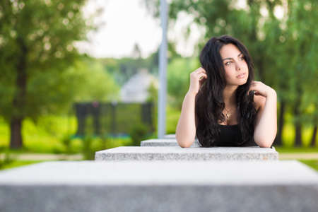 Young thoughtful brunette posing near the stone fenceの写真素材