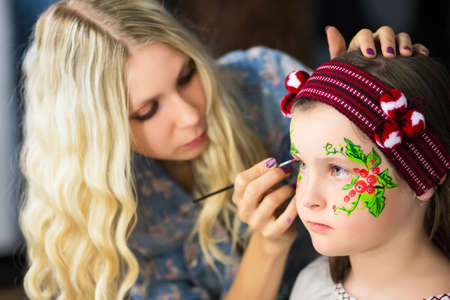 Young woman painting the face of a little girlの写真素材