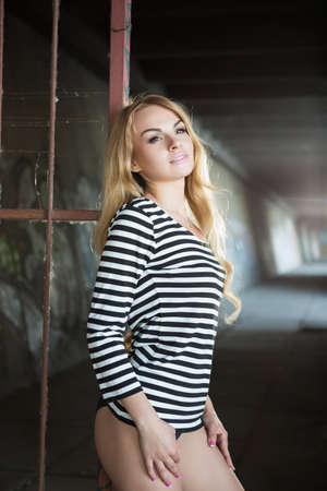 Sexy thoughtful blond woman in striped blouse posing near iron fenceの写真素材