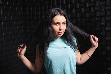 Portrait of a cheerful brunette dressed in a blue t-shirt posing on a black background