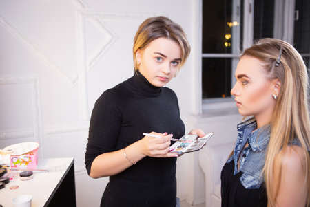 Makeup artist applying make up on nice model in the studio, against the windowの写真素材