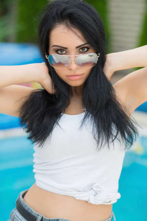 Portrait of an attractive brunette posing on the street near the pool wearing a shirtの写真素材