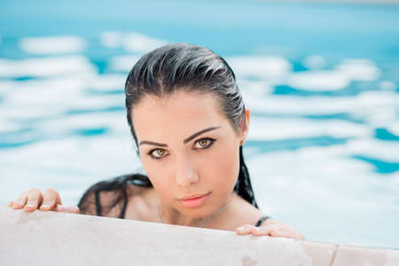 Portrait of a young pretty woman posing in the summer in the pool