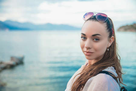 Beautiful woman posing on a background of mountains and the sea, dressed in a tunicの写真素材