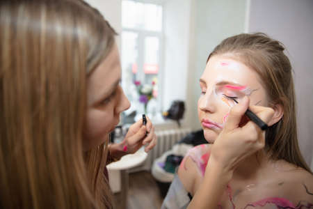The artist applies makeup to a beautiful young model in the studioの写真素材