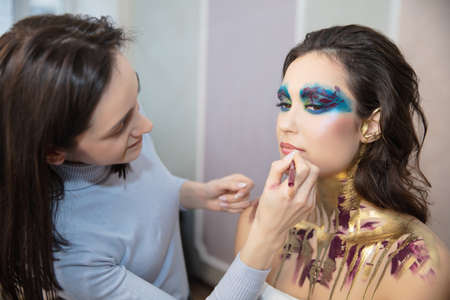 The artist applies makeup to a lovely young model in the studioの写真素材