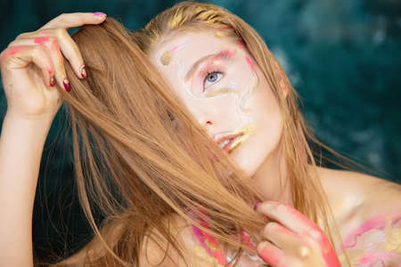 Portrait of a young attractive blonde with creative make up on her faceの写真素材