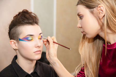 Artist applies makeup to a lovely young model in the studioの写真素材