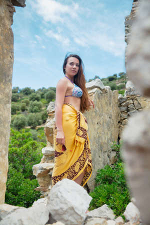 Cute woman posing among antique ruins dressed in a swimsuit and pareoの写真素材