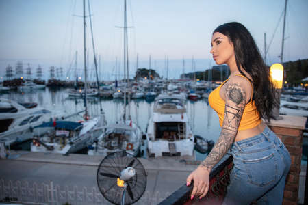 Portrait of a young woman posing on the background of the sea and yachtの写真素材