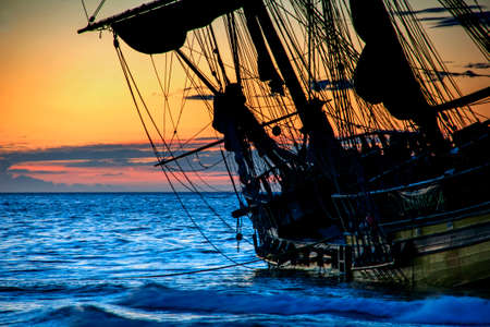 Beautiful sunrise beside a little sailboat bergantnの写真素材