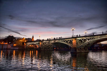 Beautiful Triana bridge next to the Guadalquivir river on its way through the city of Seville, Andalusiaの写真素材