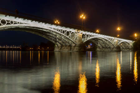 Beautiful Triana bridge next to the Guadalquivir river on its way through the city of Seville, Andalusiaの写真素材
