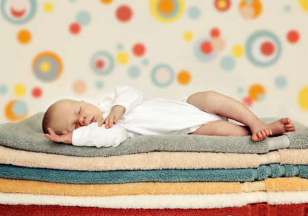 Newborn baby sleeping on colorful towels. Soft focus, very shallow DOF.の写真素材