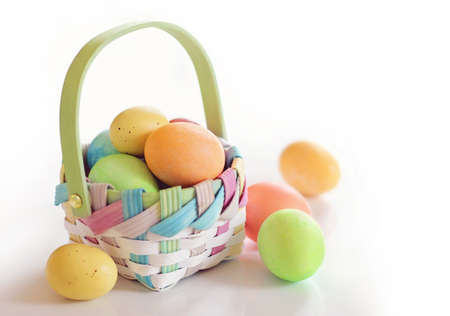 Colorful Easter eggs in a basket on white background