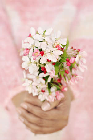 Close-up of woman's hands holding fresh spring flowers. Very shallow DOF. Selective focus on the flowers.の写真素材