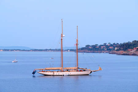 Porto Santo Stefano, Italy - August 2020: Beautiful huge sail boat with two masts anchored in the bay flies the British flag. Sailing holidays in Italy in the mediterranean seaのeditorial素材
