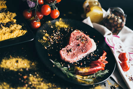 Food recipe for meat. Snack and vegetables as decoration. Tomatoes, olives, pepper on white napkin and spices scattered on black background. awesomeの写真素材