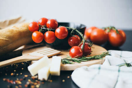 Tasty fresh tomatoes with delicious bread lying on wooden cutting board ready for cooking and making amazing meal for lunch or dinnerの写真素材