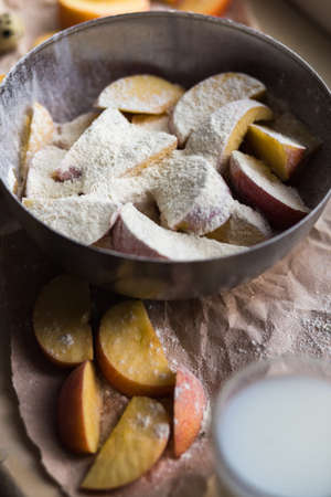 Fresh red apple slices sprinkled with flour in a stylish iron dish lying on a white window sill. A glass of milk are used as decoration.の写真素材