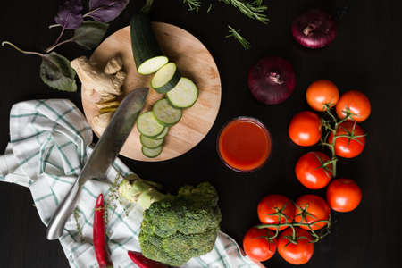 It seems like the cook just have left the slices of a squash, the ginger root and a knife on a wooden cutting board, as well as onion, red ripe tomatoes, red hot chili pepper, basil and broccoli. niceの写真素材