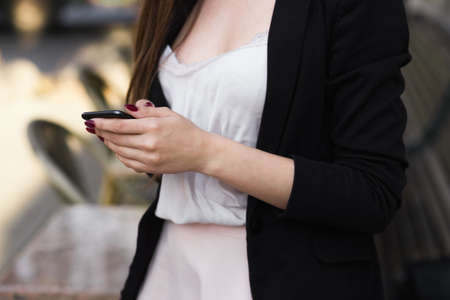 close up of fragment image of a stylish girl who holds a phone in her handsの写真素材