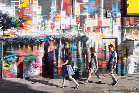 Young people walk past a colourfully painted wall in Camden Town, London.のeditorial素材