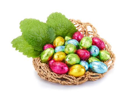 Colorful Easter Eggs in a nest with mint leaves isolated on a white backgroundの写真素材