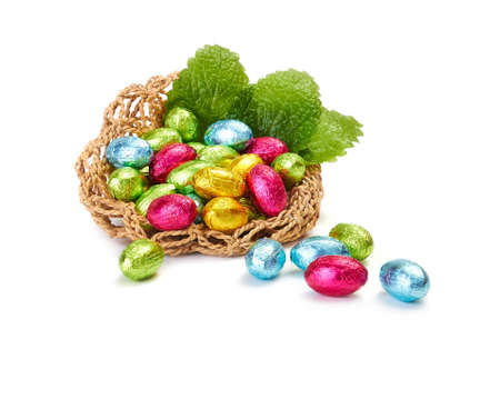 Colorful Easter Eggs in a nest with mint leaves isolated on a white backgroundの写真素材