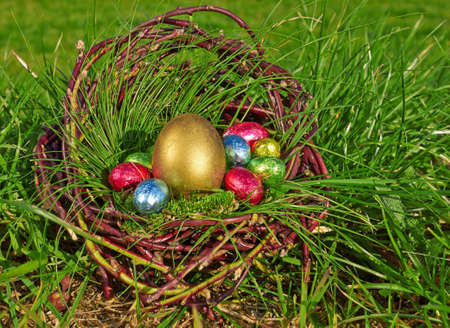 Colorful easter eggs in brown basket on grassの写真素材