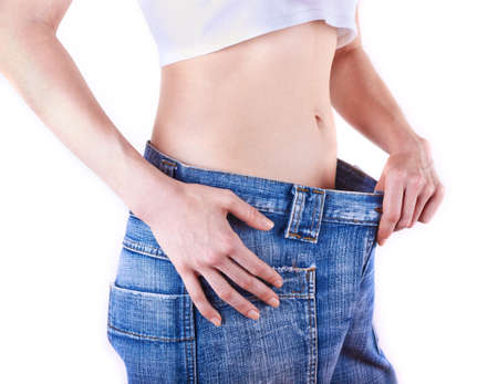 young slim woman in oversized pair of blue jeans over white background の写真素材