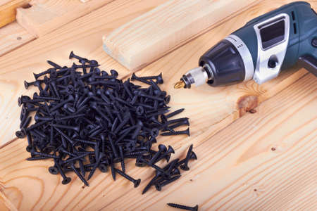 Many screws and a screwdriver on a boardsの写真素材