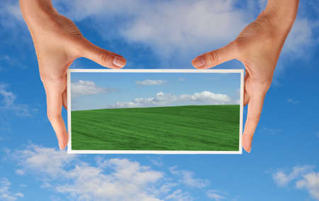 photo of green field in hands on sky background の写真素材