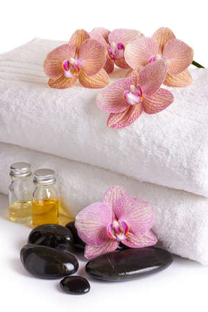 pink orchids, cosmetic oil and spa stones on white towelsの写真素材