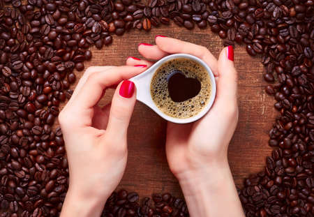 woman holding hot cup of coffee with heart shapeの写真素材