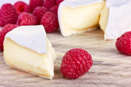 goats cheeses on wooden background with raspberryの写真素材
